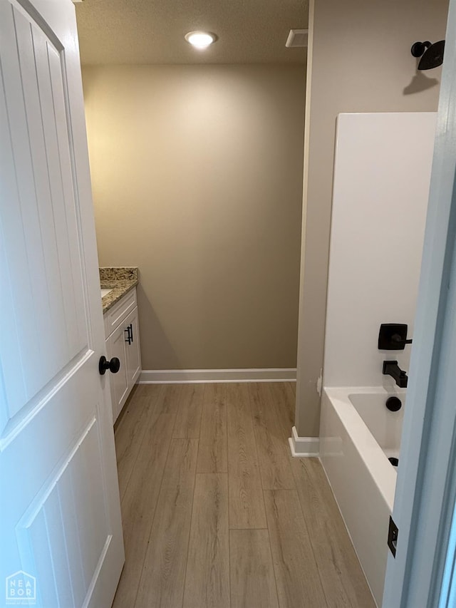 5709 Morgan Dr, Jonesboro, AR 72401 - bathroom featuring wood finished floors, vanity, a tub, baseboards, and recessed lighting