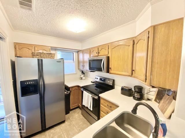 1300 S Church St, Jonesboro, AR 72401 - kitchen featuring light brown cabinetry, light countertops, a textured ceiling, a sink, and appliances with stainless steel finishes