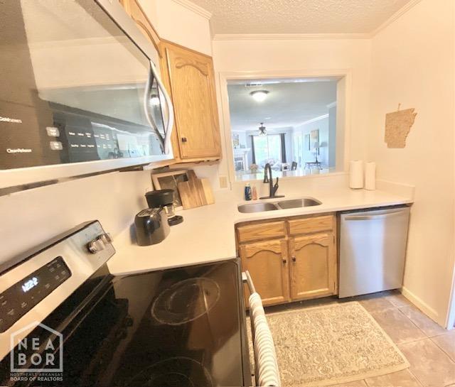 1300 S Church St, Jonesboro, AR 72401 - kitchen with light brown cabinetry, light countertops, a sink, light tile patterned floors, and stainless steel appliances