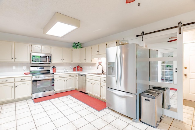 1207 Hunters Run Cv, Jonesboro, AR 72401 - kitchen with appliances with stainless steel finishes, a sink, light countertops, a barn door, and decorative backsplash