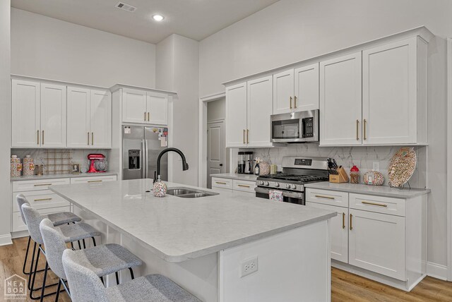 107 Hidden Creek St, Brookland, AR 72417 - kitchen featuring appliances with stainless steel finishes, a sink, a breakfast bar area, backsplash, and a center island with sink