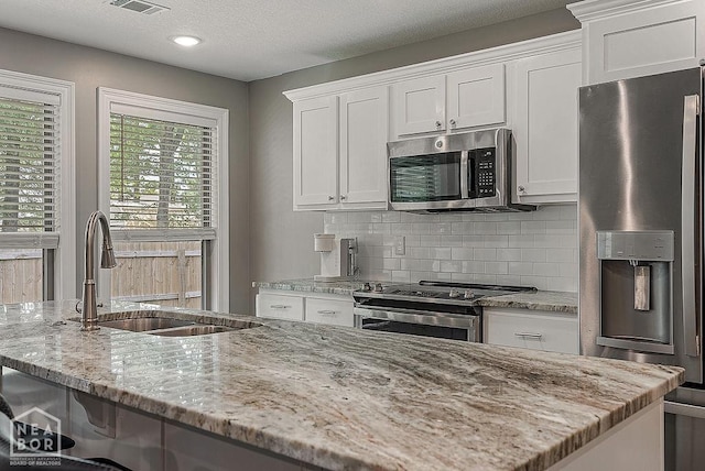 2100 N 29th St, Paragould, AR 72450 - kitchen featuring a sink, white cabinets, light stone countertops, and stainless steel appliances