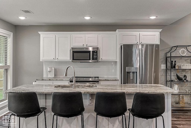 2100 N 29th St, Paragould, AR 72450 - kitchen with visible vents, appliances with stainless steel finishes, tasteful backsplash, a sink, and white cabinets
