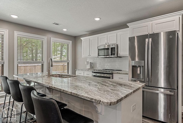 2100 N 29th St, Paragould, AR 72450 - kitchen featuring white cabinets, a sink, stainless steel appliances, tasteful backsplash, and visible vents