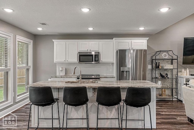 2100 N 29th St, Paragould, AR 72450 - kitchen with decorative backsplash, light stone countertops, white cabinets, dark wood-style floors, and stainless steel appliances
