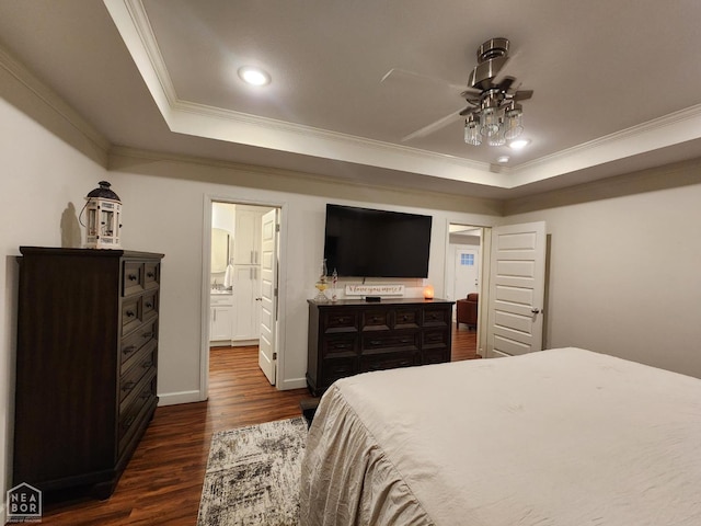 bedroom with a raised ceiling, crown molding, ensuite bathroom, and dark wood finished floors
