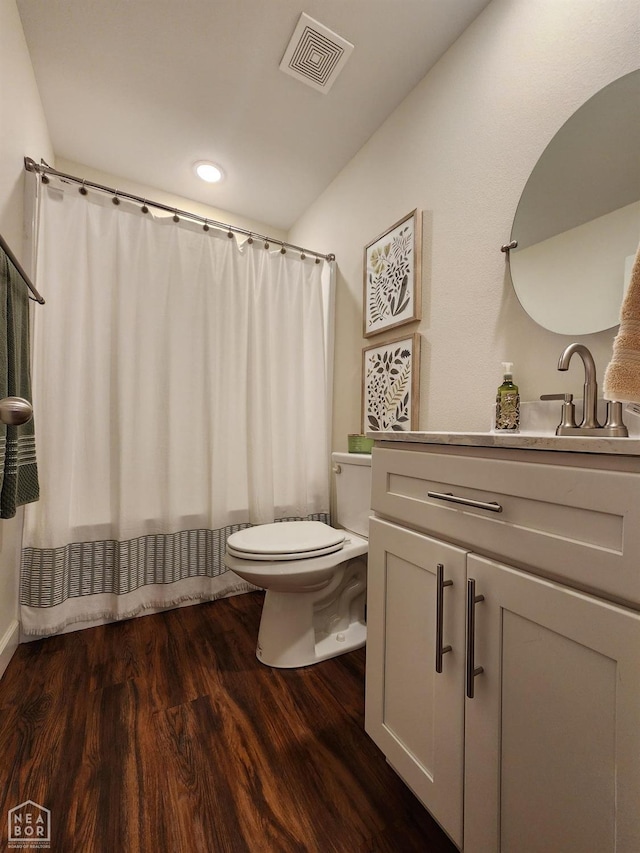 bathroom with visible vents, a shower with curtain, toilet, vanity, and wood finished floors