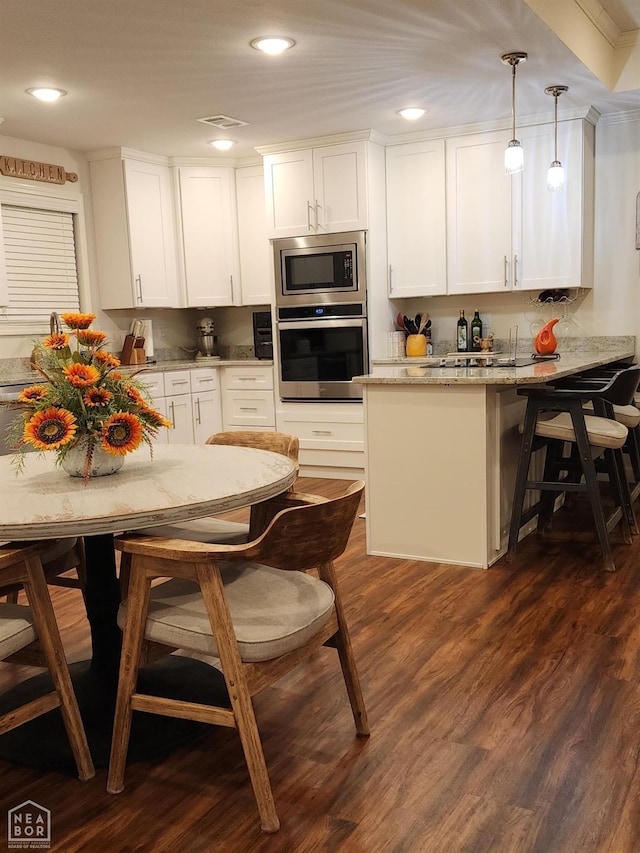 kitchen with dark wood finished floors, a peninsula, visible vents, white cabinets, and appliances with stainless steel finishes