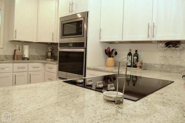 kitchen with white cabinets, light stone counters, and stainless steel appliances