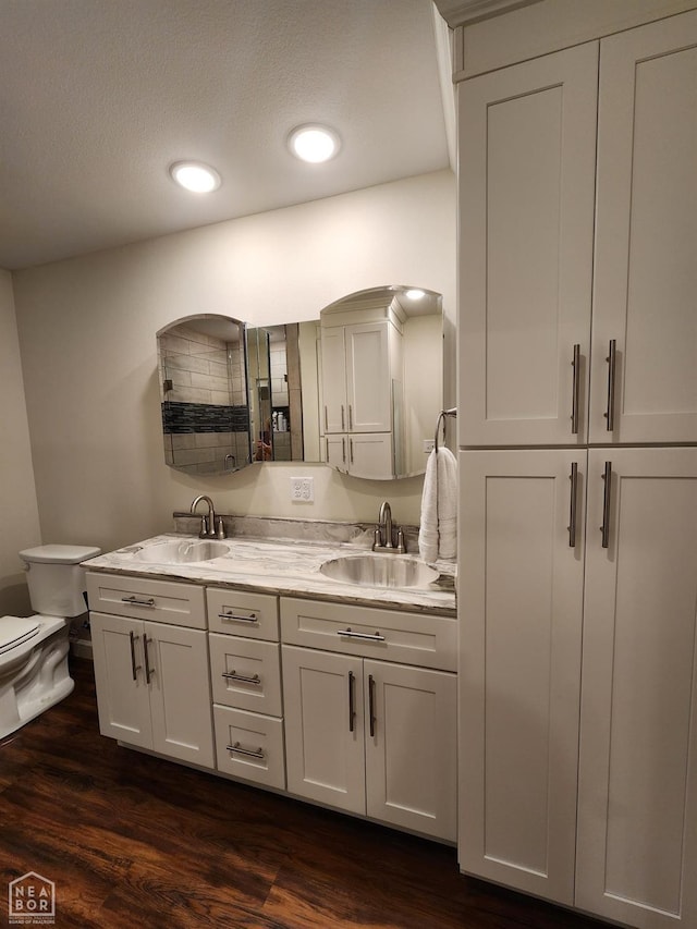 full bath with toilet, wood finished floors, and a sink