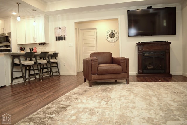 living area with baseboards, crown molding, and wood finished floors