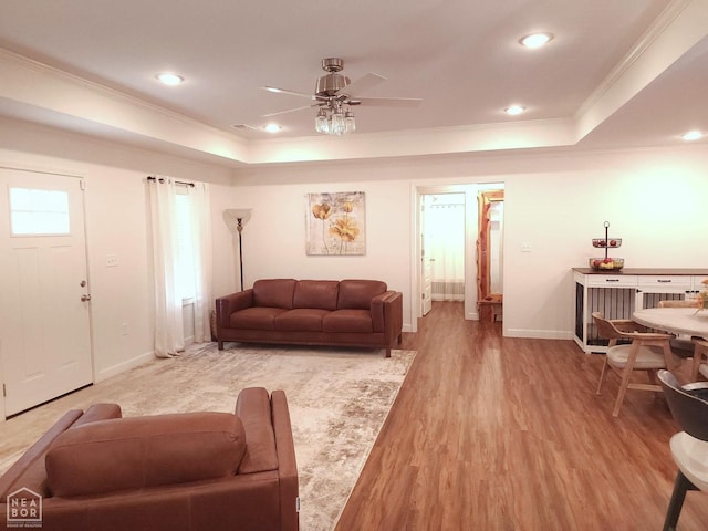 living area featuring a tray ceiling, crown molding, and a ceiling fan