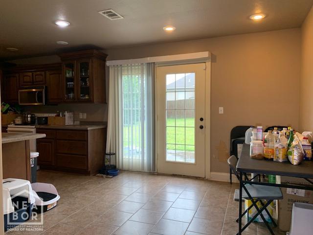 4709 Summit Ridge Dr, Jonesboro, AR 72404 - kitchen featuring stainless steel microwave, light countertops, glass insert cabinets, light tile patterned floors, and recessed lighting