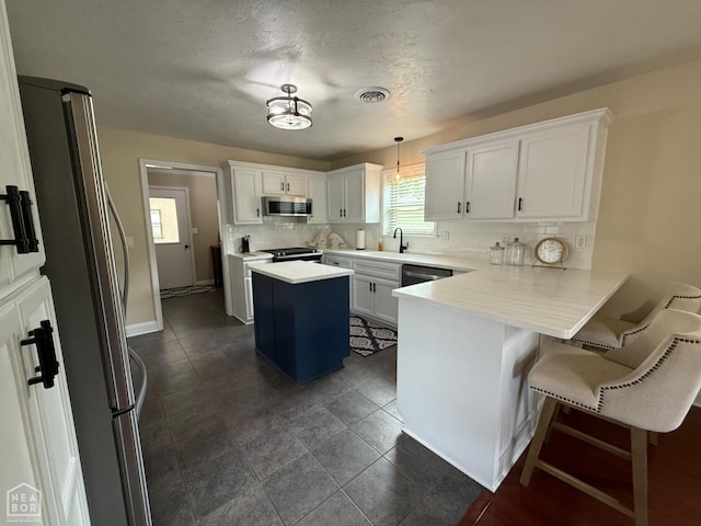 1354 Wiley Dr, Piggott, AR 72454 - kitchen featuring appliances with stainless steel finishes, decorative backsplash, a peninsula, a kitchen island, and light countertops