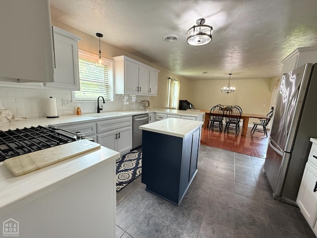 1354 Wiley Dr, Piggott, AR 72454 - kitchen with appliances with stainless steel finishes, backsplash, a peninsula, a chandelier, and decorative light fixtures