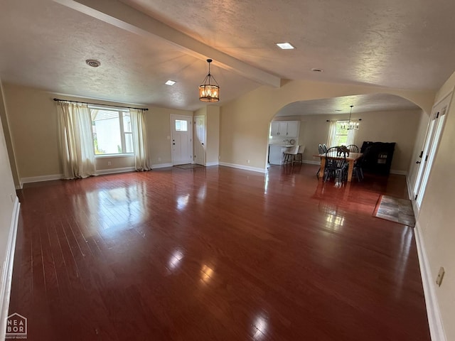 1354 Wiley Dr, Piggott, AR 72454 - unfurnished living room featuring a chandelier, arched walkways, wood finished floors, and a textured ceiling