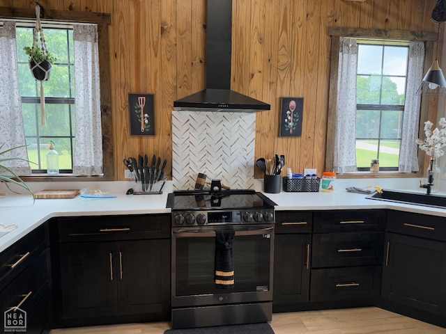 2052 Central Blvd, Bull Shoals, AR 72619 - kitchen with stainless steel range with electric stovetop, wall chimney exhaust hood, dark cabinetry, wooden walls, and light countertops
