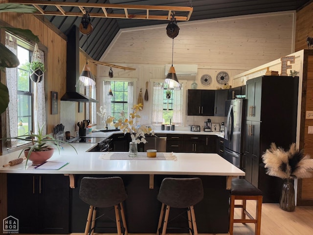 2052 Central Blvd, Bull Shoals, AR 72619 - kitchen featuring freestanding refrigerator, wood walls, wall chimney range hood, light countertops, and dark cabinetry