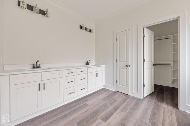 3428 Hudson Dr, Jonesboro, AR 72405 - full bath with baseboards, a sink, crown molding, a walk in closet, and wood finished floors
