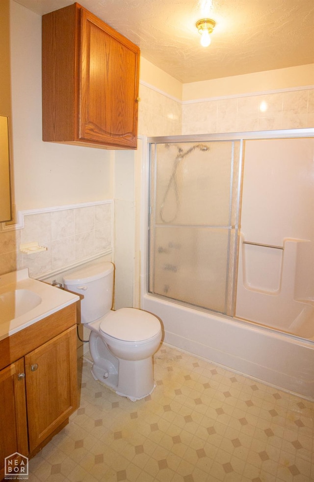 805 James Ln, Trumann, AR 72472 - bathroom with vanity, bath / shower combo with glass door, tile walls, wainscoting, and tile patterned floors