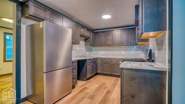 1205 Sims Ave, Jonesboro, AR 72401 - kitchen featuring freestanding refrigerator, light wood-type flooring, tasteful backsplash, dark brown cabinets, and gas range oven