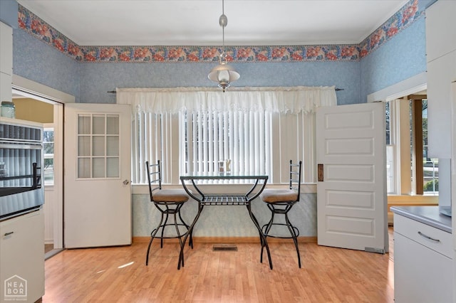 dining room with light wood-style flooring, visible vents, and plenty of natural light