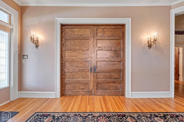 entryway featuring ornamental molding, a wealth of natural light, light wood-type flooring, and baseboards