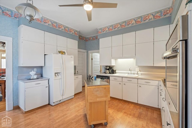 kitchen with a sink, ceiling fan, light wood finished floors, and white fridge with ice dispenser