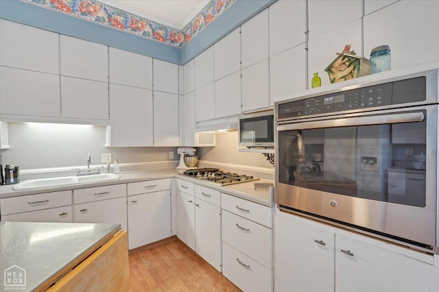kitchen with a sink, light countertops, appliances with stainless steel finishes, and white cabinetry