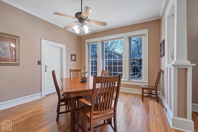 dining space with baseboards, ornamental molding, decorative columns, a ceiling fan, and light wood-style flooring