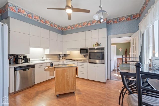 kitchen with light wood-style flooring, appliances with stainless steel finishes, light countertops, and a kitchen island