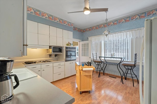 kitchen featuring a sink, light countertops, appliances with stainless steel finishes, white cabinetry, and light wood finished floors