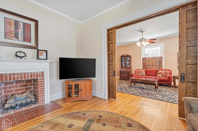 living area featuring a fireplace, baseboards, ornamental molding, and wood finished floors