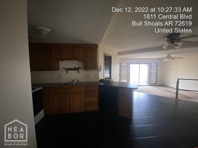 kitchen featuring a sink, open floor plan, a ceiling fan, a peninsula, and stove