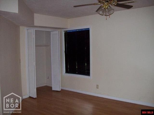 unfurnished bedroom featuring a closet, baseboards, a ceiling fan, and wood finished floors