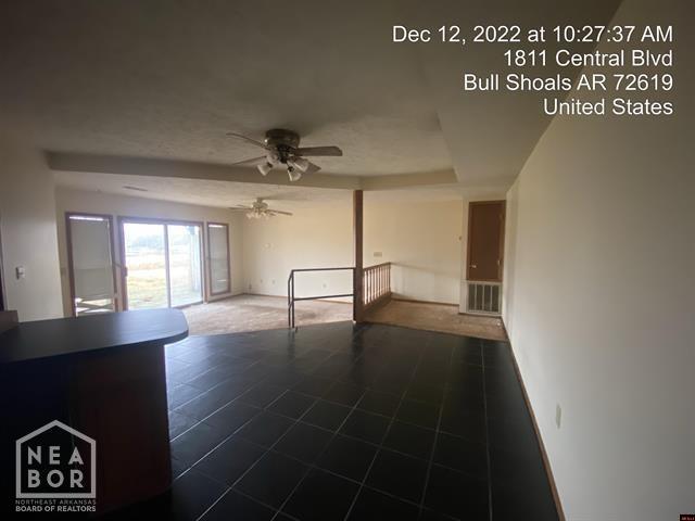 unfurnished living room with visible vents, baseboards, a ceiling fan, and a tray ceiling