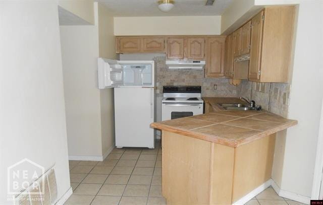 kitchen with white range with electric cooktop, under cabinet range hood, a sink, tile counters, and fridge