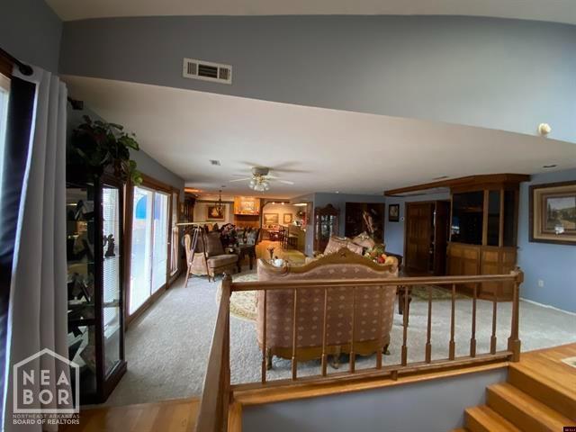 living room with carpet flooring, a ceiling fan, and visible vents