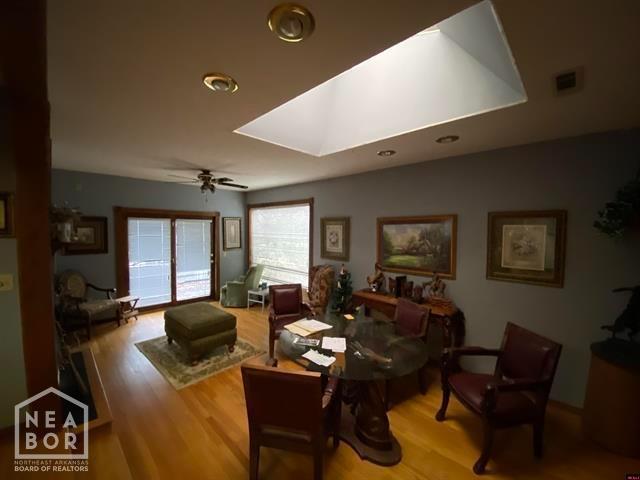 living room featuring visible vents, ceiling fan, wood finished floors, and a skylight