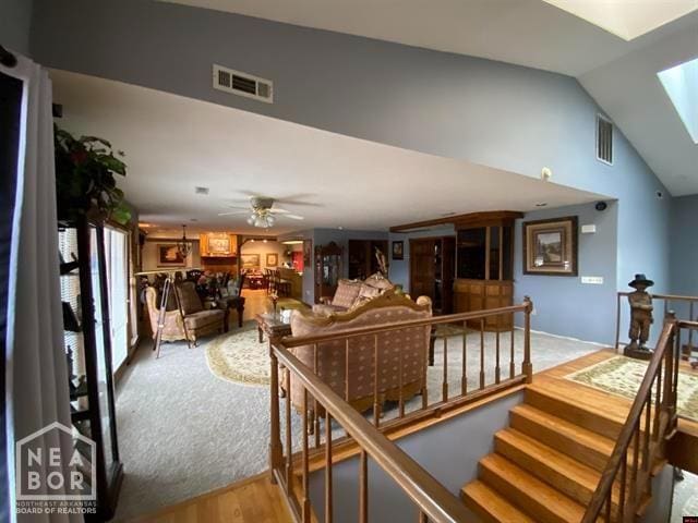 interior space with vaulted ceiling with skylight, wood finished floors, visible vents, and a ceiling fan