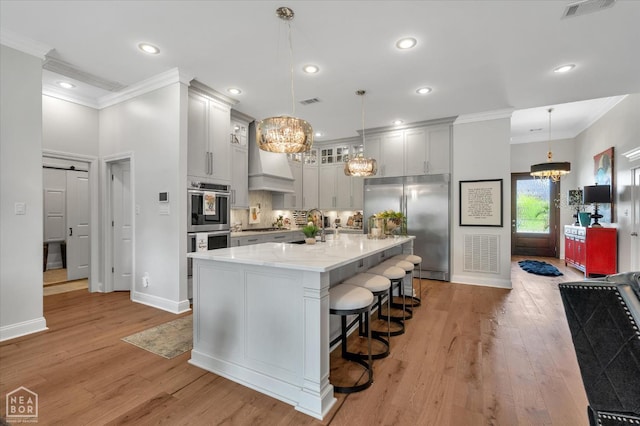 4260 Weldon Cv, Jonesboro, AR 72404 - kitchen with appliances with stainless steel finishes, a chandelier, ornamental molding, light wood finished floors, and a kitchen bar