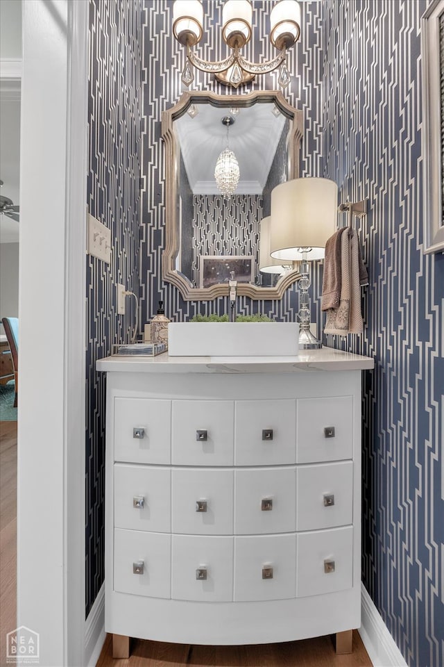 4260 Weldon Cv, Jonesboro, AR 72404 - bathroom featuring wallpapered walls, a chandelier, vanity, wood finished floors, and baseboards