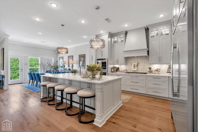 4260 Weldon Cv, Jonesboro, AR 72404 - kitchen with stainless steel appliances, custom range hood, light countertops, a center island with sink, and tasteful backsplash