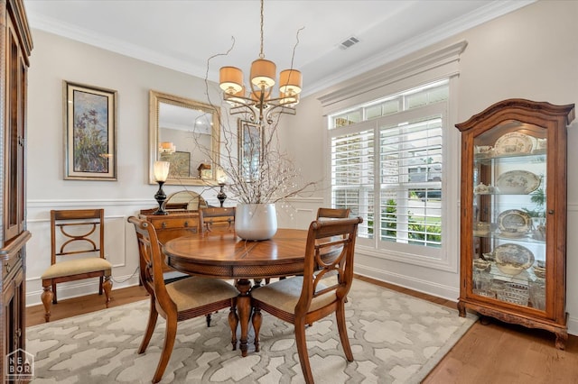 4260 Weldon Cv, Jonesboro, AR 72404 - dining room with a chandelier, crown molding, light wood-type flooring, and a wainscoted wall