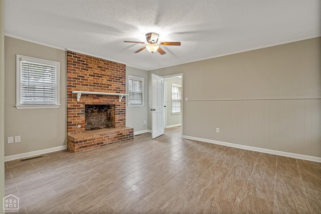 unfurnished living room with visible vents, a brick fireplace, a ceiling fan, a textured ceiling, and crown molding