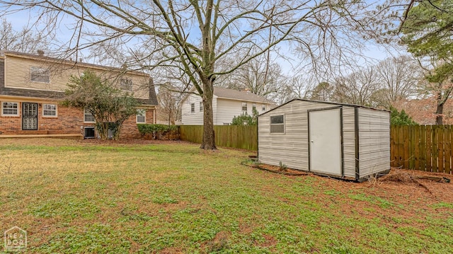 view of yard with a shed, an outbuilding, a fenced backyard, and central AC unit