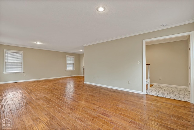 spare room with light wood-style floors, crown molding, and baseboards