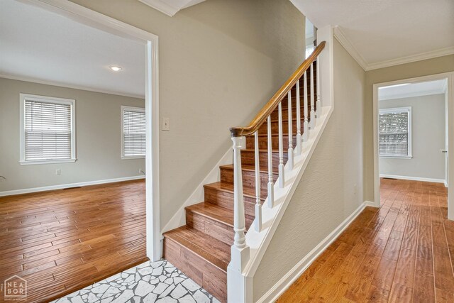 staircase with crown molding, hardwood / wood-style floors, baseboards, and a wealth of natural light