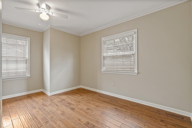 empty room featuring ornamental molding, baseboards, light wood finished floors, and plenty of natural light