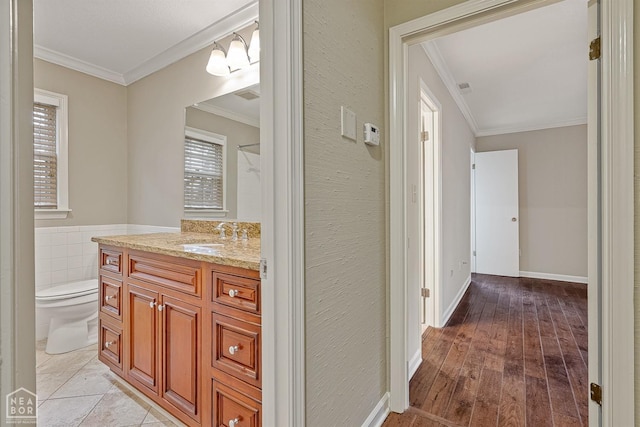 bathroom featuring toilet, wood finished floors, vanity, and ornamental molding